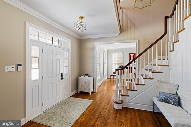 entrance foyer featuring hardwood / wood-style flooring, ornamental molding, and an inviting chandelier