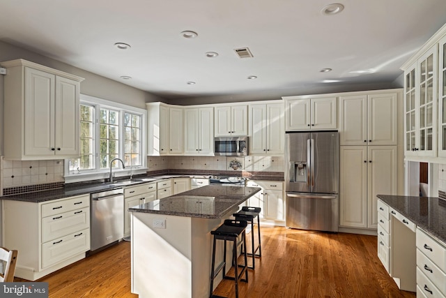 kitchen with a kitchen island, dark stone counters, white cabinets, and appliances with stainless steel finishes