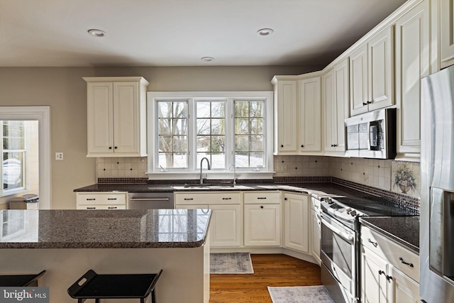 kitchen featuring sink, stainless steel appliances, white cabinets, dark hardwood / wood-style flooring, and decorative backsplash