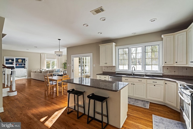 kitchen with sink, stainless steel appliances, a center island, light hardwood / wood-style floors, and white cabinets