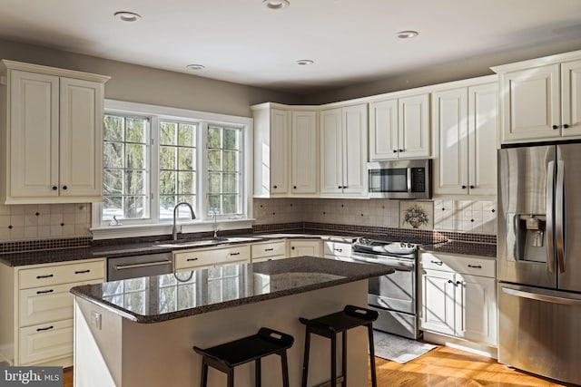 kitchen with tasteful backsplash, appliances with stainless steel finishes, a center island, and sink