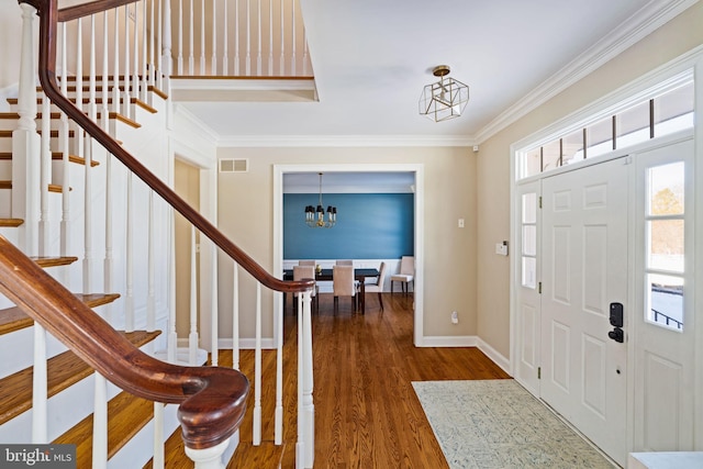 entryway with an inviting chandelier, dark wood-type flooring, and ornamental molding