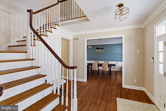 foyer featuring crown molding, dark hardwood / wood-style floors, and a chandelier