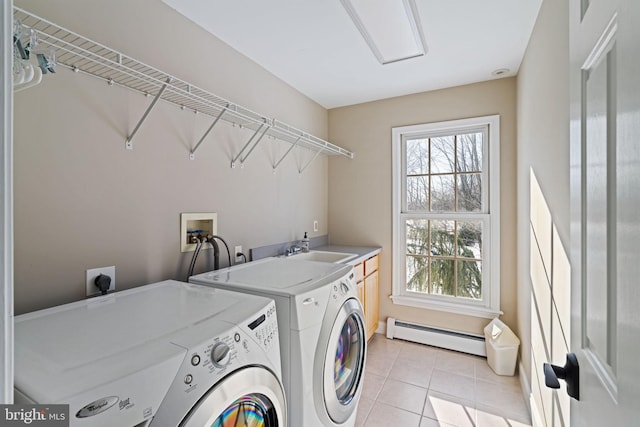 clothes washing area featuring sink, cabinets, separate washer and dryer, light tile patterned floors, and baseboard heating