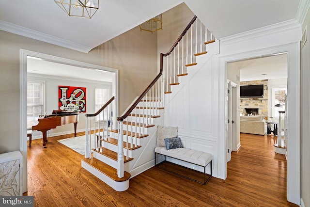 stairway with crown molding, hardwood / wood-style flooring, and a fireplace