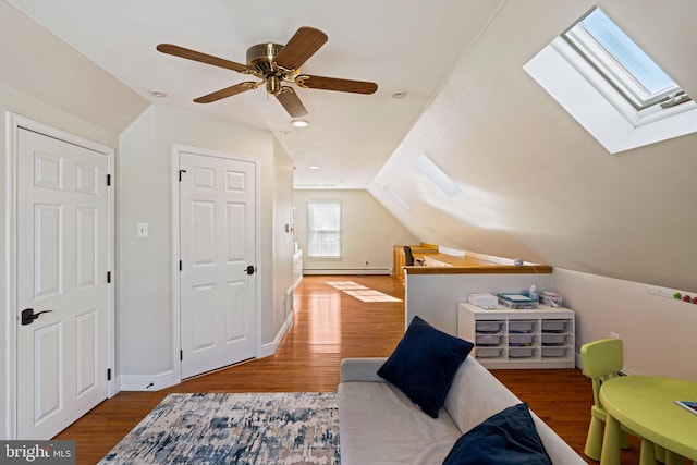 additional living space with baseboard heating, ceiling fan, wood-type flooring, and lofted ceiling with skylight