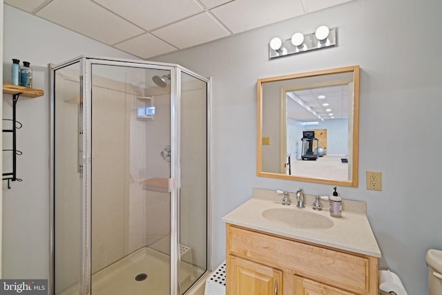 bathroom with a paneled ceiling, vanity, toilet, and an enclosed shower