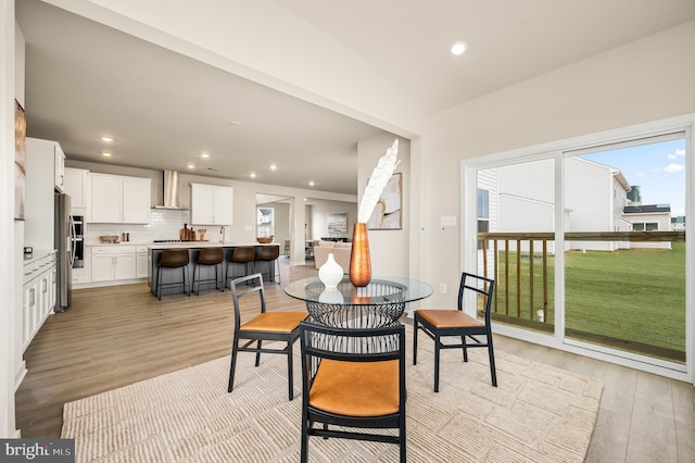 dining room with vaulted ceiling and light hardwood / wood-style floors