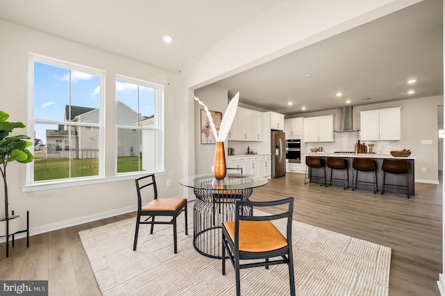 dining area with light hardwood / wood-style floors and vaulted ceiling