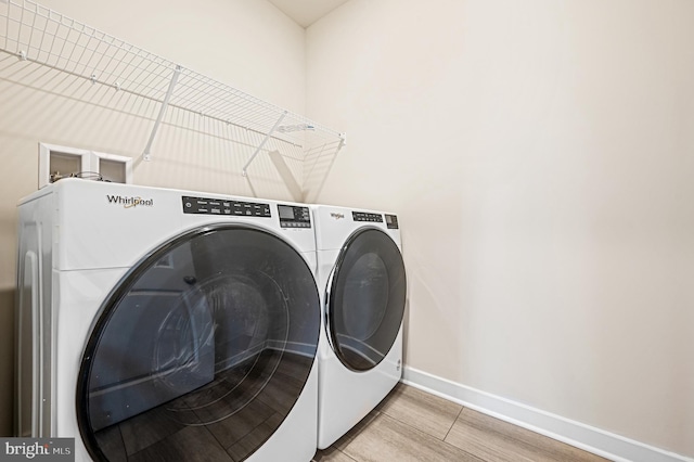 laundry area with washer and clothes dryer and light wood-type flooring