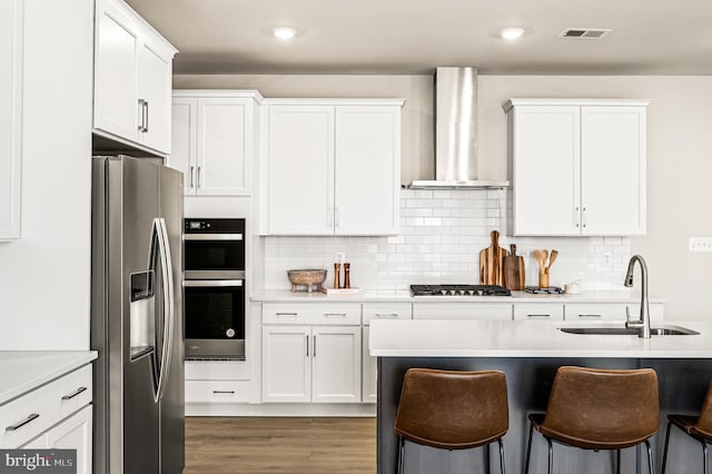 kitchen featuring white cabinets, stainless steel fridge with ice dispenser, wall chimney exhaust hood, and sink