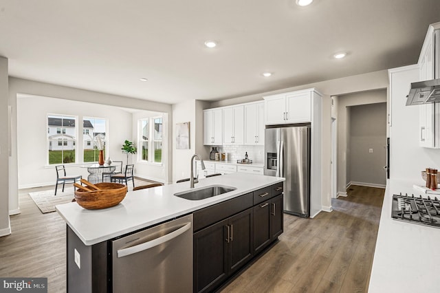 kitchen with hardwood / wood-style floors, a center island with sink, appliances with stainless steel finishes, white cabinets, and sink