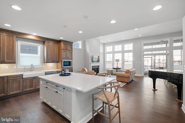 kitchen with a breakfast bar, a kitchen island, stainless steel microwave, sink, and tasteful backsplash