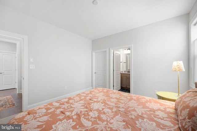 bedroom with ensuite bathroom and dark hardwood / wood-style flooring