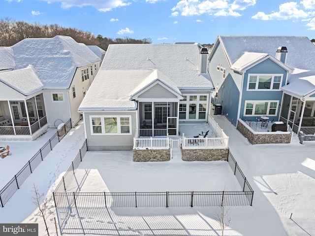 snow covered rear of property featuring a residential view, a fenced backyard, and a chimney