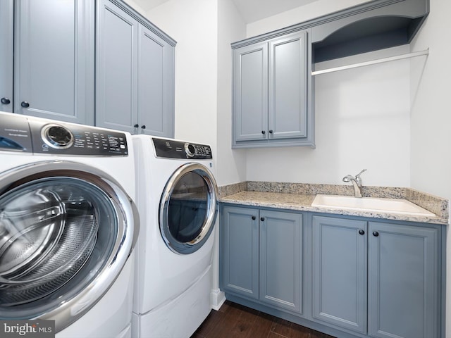 clothes washing area with cabinet space, dark wood-style flooring, washer and clothes dryer, and a sink