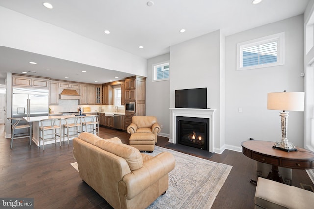 living room with dark wood-style floors, recessed lighting, baseboards, and a fireplace with flush hearth