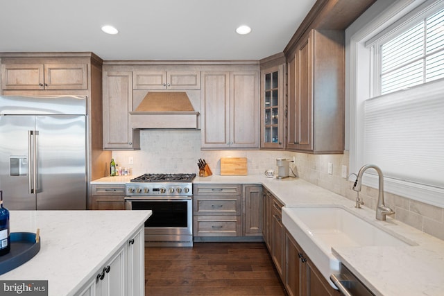 kitchen with sink, tasteful backsplash, premium appliances, and light stone countertops