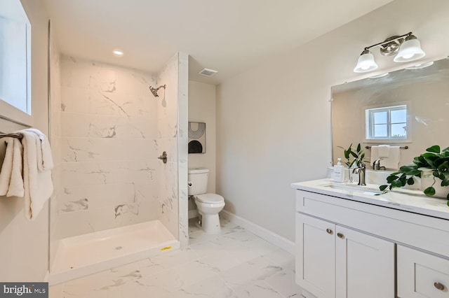 bathroom with tiled shower, vanity, and toilet