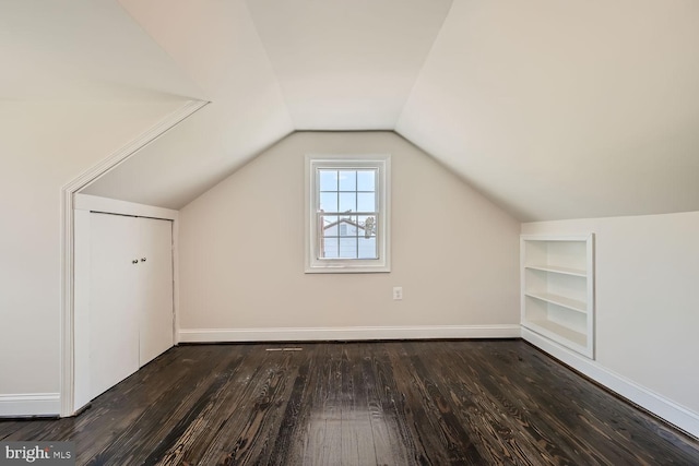 bonus room with built in features, vaulted ceiling, and dark hardwood / wood-style flooring