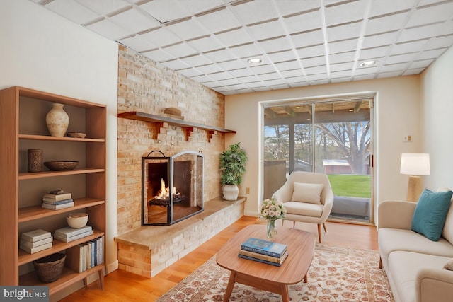 living room with light wood-type flooring and a brick fireplace