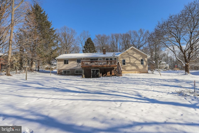 snow covered house featuring a wooden deck