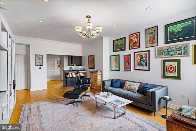 living room featuring an inviting chandelier, ornamental molding, and light hardwood / wood-style floors