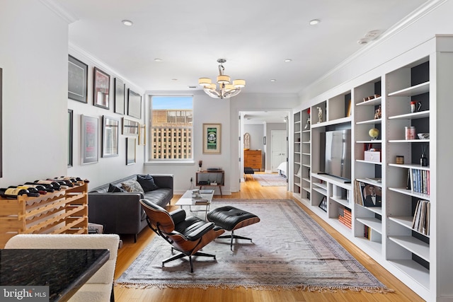 living room with an inviting chandelier, crown molding, and light wood-type flooring