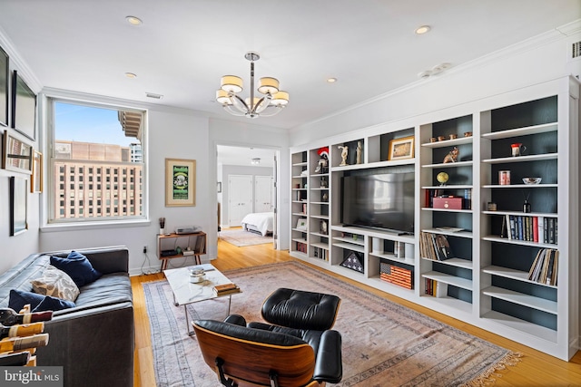 living room with ornamental molding, wood-type flooring, and a notable chandelier