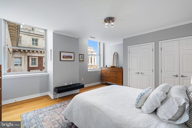 bedroom with multiple closets, ornamental molding, and hardwood / wood-style flooring