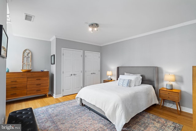 bedroom featuring crown molding, hardwood / wood-style floors, and two closets