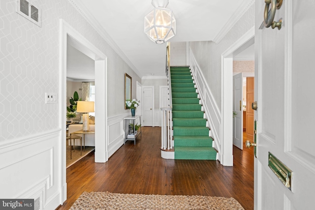 entrance foyer with an inviting chandelier, ornamental molding, and dark hardwood / wood-style floors