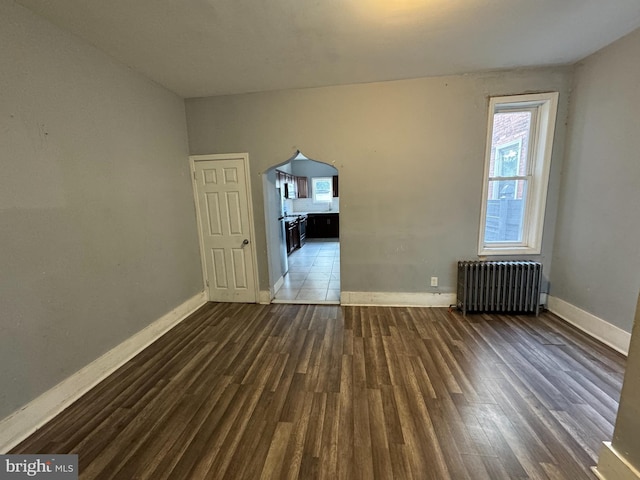 spare room featuring radiator and dark hardwood / wood-style floors