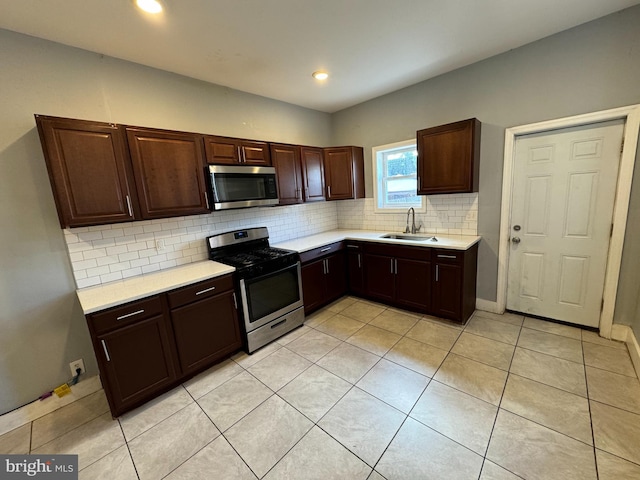 kitchen with sink, light tile patterned floors, tasteful backsplash, and appliances with stainless steel finishes