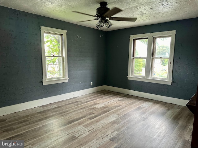 empty room with ceiling fan, light hardwood / wood-style flooring, and a textured ceiling