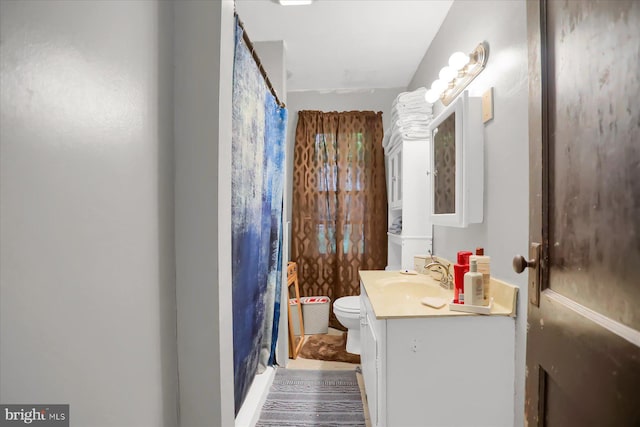 bathroom with curtained shower, vanity, and toilet