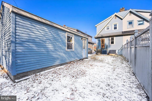 snow covered back of property featuring central AC