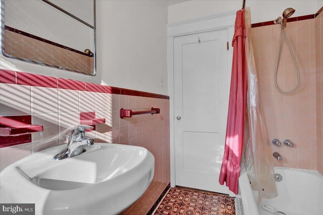 bathroom with tile patterned flooring, tile walls, shower / tub combo with curtain, and sink