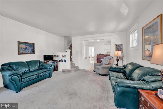 carpeted living room featuring stairs