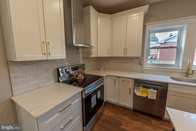 kitchen featuring wall chimney exhaust hood, backsplash, white cabinetry, appliances with stainless steel finishes, and sink