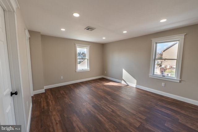 spare room featuring dark hardwood / wood-style flooring and a wealth of natural light