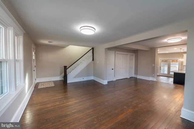 unfurnished living room featuring dark wood-type flooring and an inviting chandelier