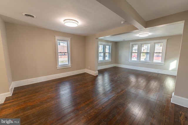 unfurnished room featuring dark hardwood / wood-style floors and beamed ceiling