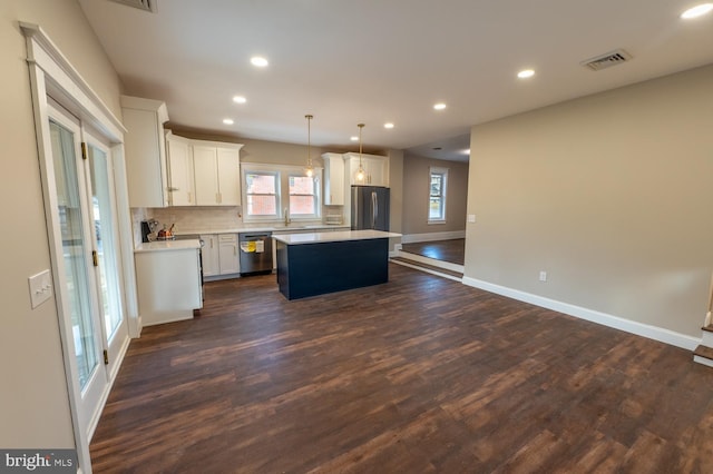 kitchen with appliances with stainless steel finishes, a center island, pendant lighting, dark wood-type flooring, and white cabinets