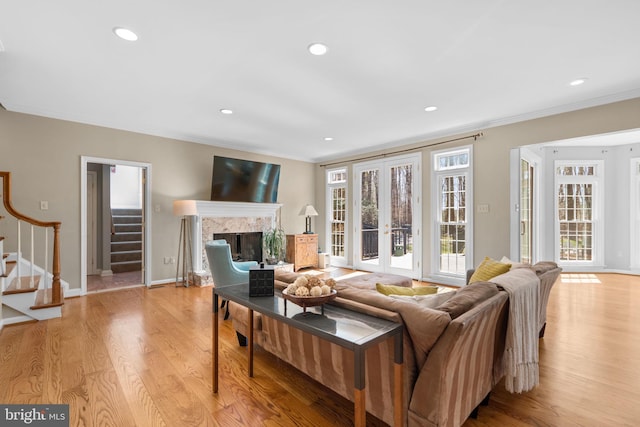living room featuring ornamental molding, french doors, light wood-type flooring, and stairs