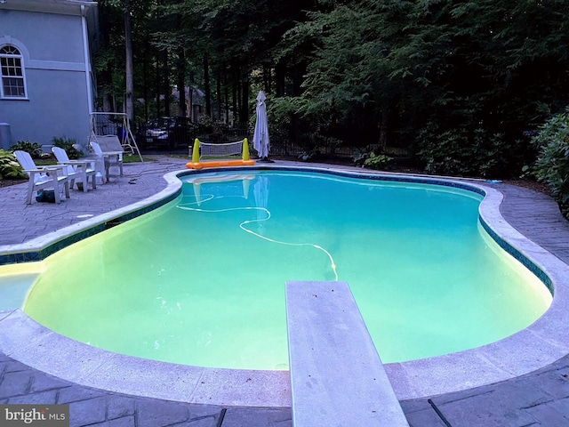 outdoor pool featuring a patio and a diving board