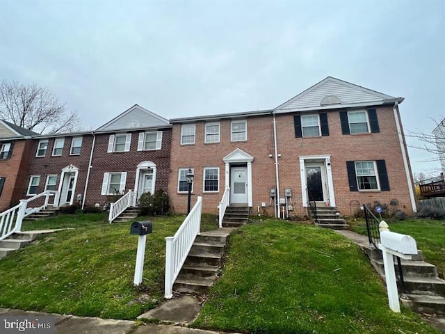 townhome / multi-family property featuring brick siding, entry steps, and a front lawn