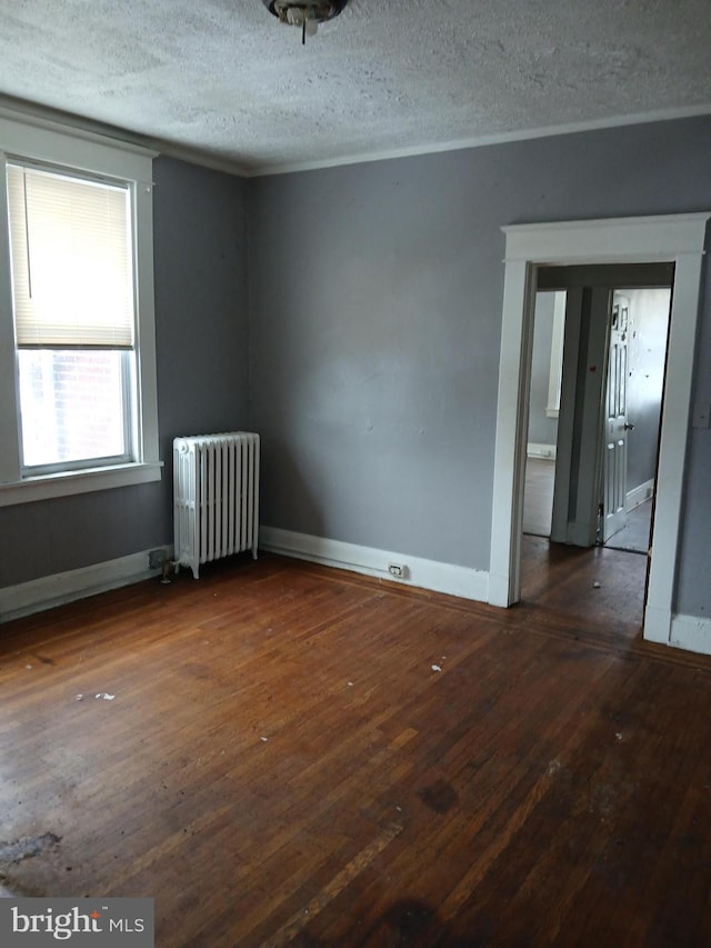 unfurnished room with dark wood-type flooring, radiator, and a textured ceiling