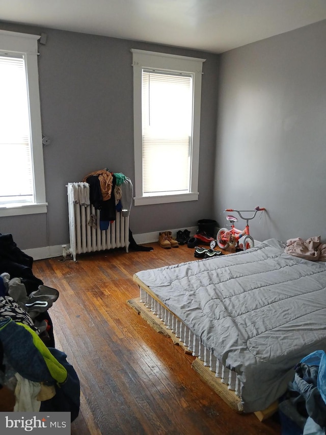 bedroom with radiator and hardwood / wood-style floors