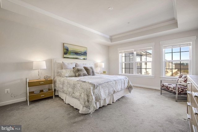 carpeted bedroom with ornamental molding and a tray ceiling